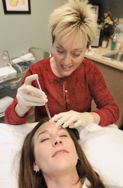 Dr. Carla Phipps injects Botox into the forehead of Karrey Britt, assistant assignment director for the Journal-World, at the Laser and Cosmetic Center in Lawrence. Botox reduces wrinkles in the forehead and eye region by temporarily paralyzing the underlying muscles.