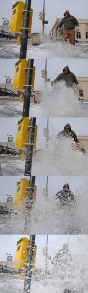 Lawrence Parks Department worker John Schrum is lost in a swirling gust of snow as he uses a snow brush to clear walkways near the intersection of Eighth and Massachusetts streets Tuesday in downtown Lawrence. Tuesday's snowfall, combined with relentless winds, made for uncomfortable walking conditions.