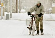 Clyde Wheatfill pushes his bicycle down a snowy street Friday in Lafayette, Ind. Heavy, wet snow made for treacherous roads and delayed commutes Friday as a huge winter storm that stretched from Texas to the Great Lakes blanketed the nation's midsection Friday.