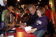 President Bush sits down to make a greeting card with Emily Mills, 5, from Horizon Elementary in Shawnee, during his tour of Hallmark Cards Inc. Friday in Kansas City, Mo.