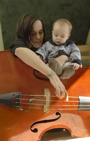 Katie Euliss plays the bass with her son, Julian, 8 months old. Euliss and her husband, Mike West, are the bluegrass duo Truckstop Honeymoon, and they home-school their children so they can be with them as they tour.
