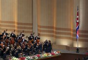 Members of the New York Philharmonic perform Tuesday next to a North Korean flag on stage in Pyongyang, North Korea.