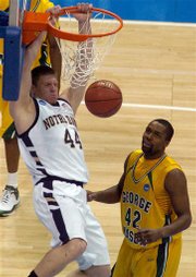 Notre Dame forward Luke Harangody, left, hangs from the rim after dunking the ball as George Mason forward Folarin Campbell looks on in the second half of Notre Dame's 68-50 victory in a first-round NCAA East Regional basketball game in Denver on Thursday, March 20, 2008.