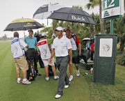 Tiger Woods, center, and Geoff Ogilvy, back left, prepare to leave the golf course on the 12th tee after a weather delay Saturday in Doral, Fla. Ogilvy leads the CA Championship by one stroke over Adam Scott. Woods is three strokes back.