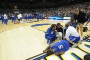 Kansas guard Rodrick Stewart (5) pounds his fist on the ground as coach Bill Self and trainers tend to Stewart's right knee. Stewart fractured his right kneecap during a dunk drill, ending his season.