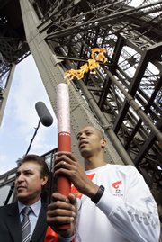 Stephane Diagana, the 400-meter world champion in 1997, carries the Olympic torch at the beginning of its relay from the first floor of the Eiffel Tower on Monday in Paris. About 3,000 French police - on motorcycles, in jogging gear and on skates - were mobilized to protect the Olympic torch relay as it departed from the Eiffel Tower.