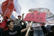 A Chinese demonstrator holds a pro-Beijing Olympic games sign in front of a demonstrator holding a sign denouncing Human Rights violations by Chinese authorities Friday in Buenos Aires prior to the Olympic Torch touring.