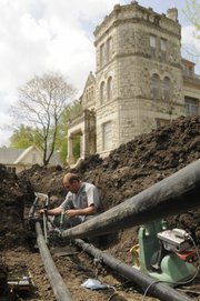 Jeron Fuller, of Evans Energy Development in Paola, connects pipes Thursday to a geothermal system that will use the heating and cooling power of the Earth to reduce utility expenses at the Castle Tea Room, 1307 Mass.