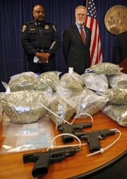 San Diego State University president Stephen Weber, right, and SDSU chief of police John Browning, left, stand over a guns and drugs seized during the arrest of 96 people on drug charges Tuesday in San Diego. Seventy-five SDSU students and 21 nonstudents were arrested after an undercover investigation of the college drug ring.
