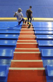 Tim Brown, left, and Eric Ivins, general maintenance repair technicians for the Kansas University Athletics Department, clean the stands inside Allen Fieldhouse in preparation for this weekend's high school graduations. Temperatures are expected to reach 86-degrees on Sunday for both LHS and FSHS graduations. With no air conditioning in Allen Fieldhouse, organizers are planning for a steamy Sunday.
