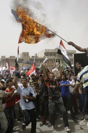 Protesters shout slogans as a burning American flag is waved Friday during a rally in the Shiite enclave of Sadr City, Iraq.