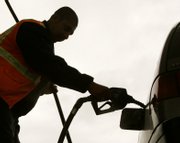 Station attendant Jorge Reyez pumps gas in Salem, Ore. Oil prices shot up more than $10 to a record above $139 Friday. In response to rising costs, employers are coming up with creative ways to save gas, such as allowing employees to telecommute or condensing the work week to four days. See story, page 7A.