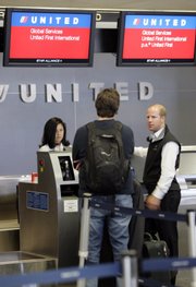 United Airlines first class passengers check in at San Francisco International Airport in this June 4 file photo. Comparing rates of as many airlines as possible is one way to save money on flights this summer.