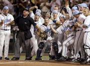 Umpire Tony Walsh holds back celebrating North Carolina players who are waiting by home plate to greet Chad Flack, who hit the go-ahead, two-run home run against Fresno State in the eighth inning of a College World Series game Saturday in Omaha, Neb. North Carolina beat Fresno State, 4-3, to force a rematch at 6 tonight.