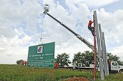 Workers from the Kansas Turnpike Authority erect a road sign announcing the exit for Kansas University two miles east of the East Lawrence exit on I-70. The new sign, which lays claim to Kansas' status as an international research university, 2008 NCAA Men's Basketball Champions and 2008 Orange Bowl Champions, was installed on Wednesday at mile marker 207.