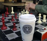 Men play chess over a cup of Starbucks coffee Tuesday in Alameda, Calif. Starbucks Corp. said Tuesday it would close 600 company-operated U.S. stores in the next nine months.