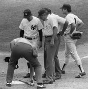 New York Yankees manager Billy Martin, second from left, watches as umpire Tim McClelland uses home plate to measure pine tar on the bat of Kansas City's George Brett in this file photo from July 24, 1983. Brett used the bat to homer in the ninth inning, apparently giving the Royals the victory, but the bat was declared illegal.