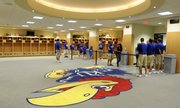 Visitors pass by the giant Jayhawk on the carpet of the locker room Wednesday during an open house tour of the Anderson Family Football Complex.