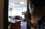 A visitor leans in to grab a photo of Kansas football coach Mark Mangino's office overlooking Kivisto Field on Wednesday during an open house tour of the Anderson Family Football Complex.