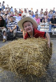 Colin Galiano, 3, heaves a 15-pound hay bale onto a platform during the 2008 hay bale throwing contest at the Douglas County 4-H Fairgrounds. The contest came before the demolition derby rally.