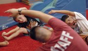 Boys in a beginning gymnastics class stretch along with their instructor during a practice recently at the East Lawrence Recreation Center.
