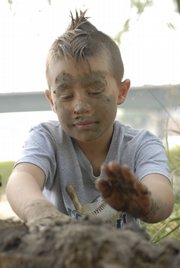 Toby Meyer, 8, packs the walls of the mud fort along the banks of the Kansas River. Toby and his father, Tom, helped to build the structure.