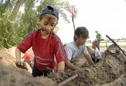 Allen Meyer, 9, left, and his brother, Trysten, 11, pack the sides of a mud fort that they and others built Tuesday along the Kansas River north of Constant Park, near Sixth and Tennessee streets. Lawrence children and their parents joined forces in the morning to re-create the fort, a common structure that pioneers and Civil War-era troops used as a lookout and for security. About two dozen youngsters participated in building two mud forts.