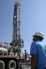 Workers with Evans Energy Development, Paola, drill wells Wednesday for an energy-saving geothermal climate-control system at Westar Energy's new service center, 746 E. 27th St. in Lawrence. At right is Pat Tryon, project architect for Westar Energy.
