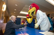 Hal Sandy autographs postcards with a couple of Jayhawk mascots in this 2005 photo courtesy of University Relations.
