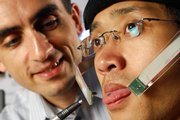 Maysam Ghovanloo, assistant professor at Georgia Tech, points to a tiny magnet on graduate student Xueliang Huo's tongue in Atlanta. The device will turn Huo's tongue into a joystick that controls a wheelchair, and the research team developing the process hopes it could help the disabled gain more mobility.