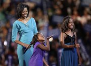 Sasha Obama, 7, daughter of presidential candidate Barack Obama, blows a kiss to her father while he addresses the Democratic National Convention on Monday in Denver by a satellite feed. Looking on are Michelle Obama, left, the candidate's wife, and daughter Malia, 10.
