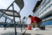 J.D. Loudabarger, assistant athletic director for event management, works Wednesday under the sun removing the old numbers from the wheelchair-accessible platform seats so they may be renumbered. Various crews have been busy working in and around Memorial Stadium in preparation for Saturday's home-opener against Florida International.