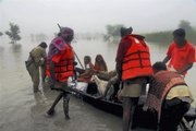 Rescuers help people to safer areas in Patna, India, on Saturday. A rescue boat filled with flood victims capsized and killed 20 people in northern India, where monsoon flooding grew worse because of heavy rain and water flowing from neighboring Nepal, officials said Saturday.