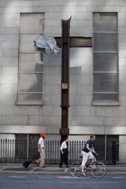 People pass a steel cross, a remnant of the attacks on the World Trade Center, now being stored at a church close to the infamous site. As the nation prepares for the seventh anniversary of Sept. 11, 2001, many have mixed feelings about the day that changed U.S. history yet grows more remote with each passing year.