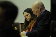 Ramona Morgan talks with her attorney, Billy Rork, Monday in Douglas County District Court. Behind them is a photograph of the truck that police say Morgan was driving when two U.S. Highway 59 workers were struck and killed on Sept. 11, 2007.