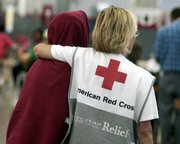 In this Sept. 6, 2005, file photo, American Red Cross volunteer Maurrie Sussman, right, comforts a New Orleans resident at the Veterans Memorial Coliseum in Phoenix.