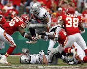 Oakland Raiders running back Justin Fargas (25) leaps over teammate Robert Gallery and through Kansas City Chiefs linebacker Derrick Johnson, left, and DaJuan Morgan. The Raiders routed the Chiefs, 23-8, on Sunday in Kansas City, Mo.