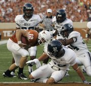 Texas quarterback Colt McCoy (12) escapes a handful of Rice defenders as he scrambles over his right end for an eight-yard touchdown Saturday in Austin, Texas. McCoy later passed Major Applewhite for the Texas all-time record in touchdown passes with 62.
