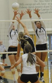 Above, Free State's Alex Mollohan, left, and Taylor Manning reach for a block against Blue Valley. Blue Valley won, 2-0, on Thursday at Free State, but the Firebirds clinched the league title.