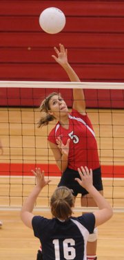Lawrence High senior Maddy Orth lofts a shot over the net past Manhattan High freshman Mari Jo Massanet. The Lions lost their three matches on Tuesday at LHS.