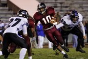 Lawrence High's Tyrae Jenkins (10) tries to slide past Olathe Northwest Raven defenders. Jenkins ran for a touchdown in the Lions' 28-7 victory Friday at Haskell Stadium.
