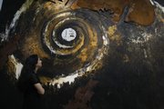 A Christie's employee poses Monday for photographs in front of an untitled piece by Enzo Cucchi, which was featured in an Italian sale that took place Monday evening at the auction house's offices in London. The global economic crisis is being felt in the art world, with prices for many works plunging.