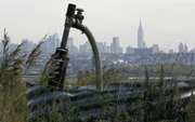 A methane gas collection pipe sticks out of the 1-E landfill in Kearny, N.J., with a view of the New York skyline behind. The Kearny site is among 21 landfills in New Jersey that convert methane gas produced by decomposing trash into electricity, according to the state Board of Public Utilities.