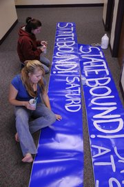Perry-Lecompton seniors Kali Roberts, foreground, and Stephanie Horton, paint a banner Tuesday for the school's high school football championship game. The Kaws will play Topeka-Hayden for the state 4A championship Saturday in Salina.