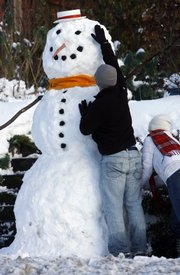 Jeff Olson puts the finishing touches on an 8-foot snowman built by him and his girlfriend, Veronica Nim, in front of Nim’s house in West Seattle. “It’s not the biggest one we’ve done,” Olson said, recalling a 15-footer he built with the help of a football team several years back. Heavy snowfall and sub-zero temperatures are causing big problems across the U.S.