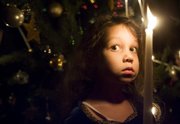 Sofia Thomas, 5, holds a candle during a Christmas tree lighting ritual at a holiday party Sunday at the residence of Serina Hearn and Tony Backus, 1941 Mass.