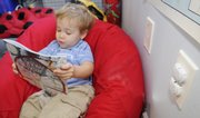 Sebastian Borjas sits down to read a book at his house where his mother, Sarah Borjas, operates Boomer Babies Day Care in Lawrence. Borjas has installed heavy-duty electric socket covers, visible at right, and fenced off areas of her home to help keep Borjas safe.