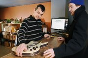 Sean Passmore, owner of Bling Drop-off Store, looks at a guitar brought in by KU student Dave Clothier. Passmore hopes his start-up business will make it through the recent economic recession. Passmore will try to sell Clothier's guitar on eBay.