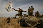 An Israeli soldier jumps off an armored vehicle carrying a flag of Israel's 60th anniversary as he celebrates with his unit their return from the Gaza Strip on the Israeli side of the border, Friday Jan. 16, 2009. Top Israeli diplomats headed for Egypt and the United States on Friday in what appeared to be a final push toward a cease-fire to end Israel's punishing Gaza offensive against Hamas militants.
