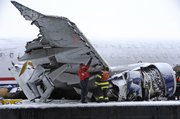 The badly damaged wing and engine of the US Airways Airbus A320 is inspected out of the water on a barge, Sunday, Jan. 18, 2009, in New York. Workers plan to remove the plane during the day to an undisclosed location.